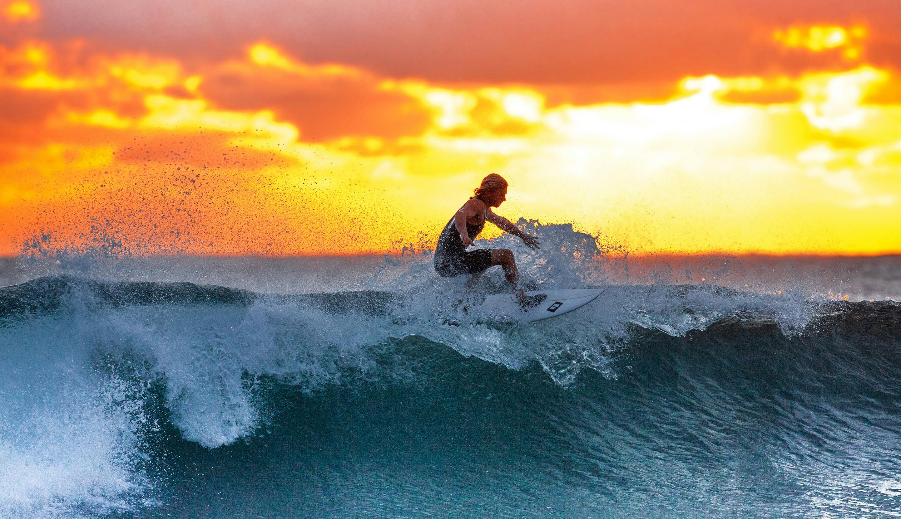 Surfers walking out at a Tamraght pointbreak at golden hour